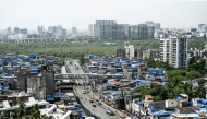 This photograph taken on July 12, 2025 shows high-rise buildings around the cramped shanties of Dharavi, a slum settlement in Mumbai. (Photo by Indranil Mukherjee / AFP)