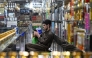 An Afghan vendor selling perfume and body sprays, uses his mobile phone as he sits at his shop in Kabul on October 1, 2025.  (Photo by Wakil Kohsar / AFP)
