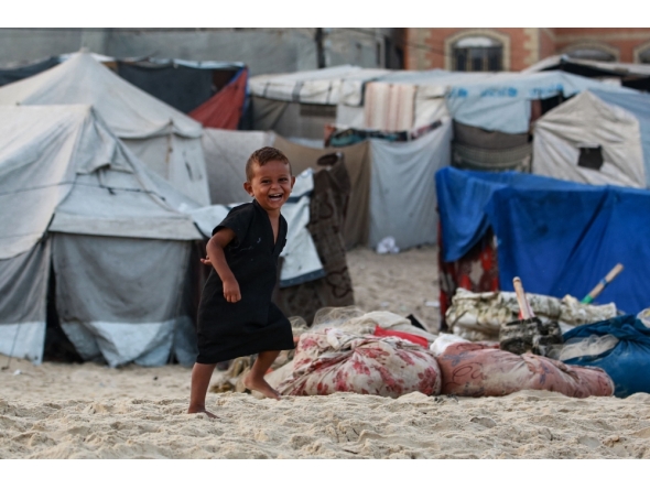 A displaced Palestinian child runs amid tents used as temporary shelter, in Deir el-Balah in the central Gaza Strip, on October 5, 2025. (Photo by Bashar Taleb / AFP)