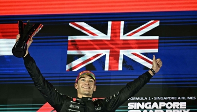First-placed Mercedes' British driver George Russell celebrates on the podium after the Formula One Singapore Grand Prix night race at the Marina Bay Street Circuit in Singapore on October 5, 2025. (Photo by Lillian SUWANRUMPHA / AFP)