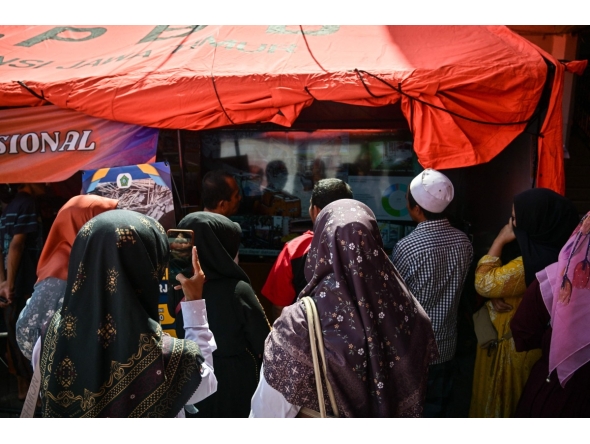 Relatives of missing students watch a live broadcast of the rescue operation near the collapsed Al Khoziny Islamic boarding school in Sidoarjo, East Java, on October 6, 2025, as recovery efforts continue. Photo by JUNI KRISWANTO / AFP