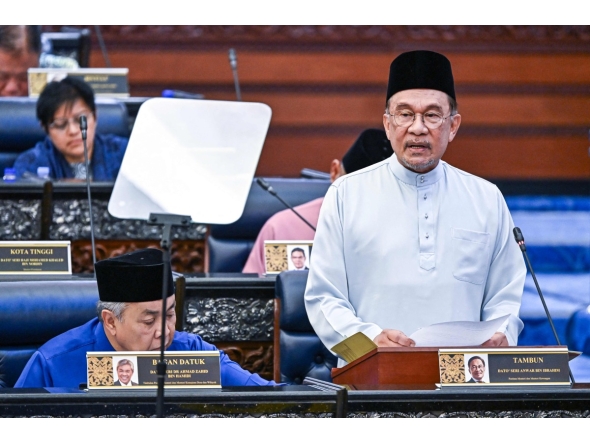 This handout photo taken and released by Malaysia's Department of Information on October 10, 2025 shows Malaysia's Prime Minister and Finance Minister Anwar Ibrahim delivering his speech on the 2026 national budget at the Parliament in Kuala Lumpur. (Photo by Nazri RAPAAI / DEPARTMENT OF INFORMATION / AFP