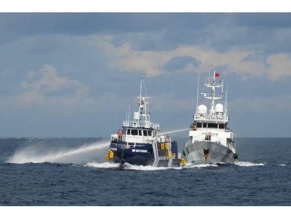 This handout photo taken and released on October 12, 2025 by the Philippine Coast Guard shows a China Coast Guard ship (R) deploying water cannon as a Philippine Bureau of Fisheries vessel (L) is seen alongside during an incident near Thitu island in disputed waters of the South China Sea. Photo by Handout / Philippine Coast Guard (PCG) / AFP