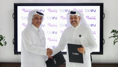 beIN Consumer Sales Manager Hamad Aljaber and Rafeeq Media Manager Ahmed Abdulla exchange documents during the ceremony. 