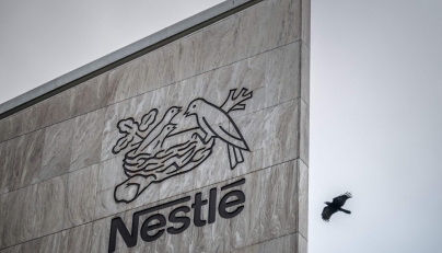 This photograph shows a bird flying next to the logo of Swiss food giant Nestle on the facade of its headquarters, in Vevey, western Switzerland, on October 14, 2025. (Photo by Fabrice Coffrini / AFP)