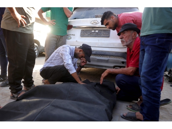 Friends and relatives mourn over the shrouded body of a man killed in an Israeli strike earlier, as he is brought to Deir al-Balah's Shuhada al-Aqsa hospital in the central Gaza Strip on October 19, 2025. (Photo by BASHAR TALEB / AFP)
