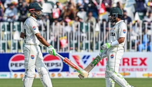 Pakistan's captain Shan Masood (L) and his teammate Babar Azam bump their bats during the first day of the second Test cricket match between Pakistan and South Africa at the Rawalpindi Cricket Stadium in Rawalpindi on October 20, 2025. (Photo by Aamir QURESHI / AFP)

