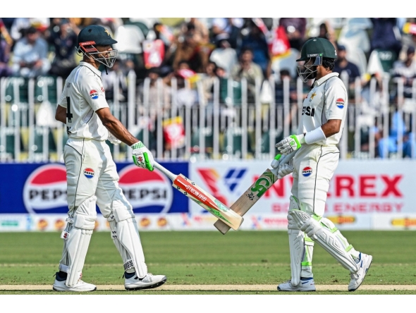 Pakistan's captain Shan Masood (L) and his teammate Babar Azam bump their bats during the first day of the second Test cricket match between Pakistan and South Africa at the Rawalpindi Cricket Stadium in Rawalpindi on October 20, 2025. (Photo by Aamir QURESHI / AFP)

