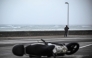 A person holds on to a lamppost as an overturned scooter is seen on a street on October 23, 2025 in San Sebastian, northern Spain, amid strong winds and a rough sea. (Photo by ANDER GILLENEA / AFP)