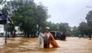 A woman wearing a raincoat wades through a flooded street in Hue on October 28, 2025. Photo by AFP