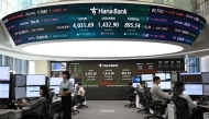 Currency dealers monitor exchange rates in front of a screen showing South Korea's benchmark stock index and the Korean won/USD exchange rate in a foreign exchange dealing room at the Hana Bank headquarters in Seoul on October 27, 2025. (Photo by Jung Yeon-je / AFP)
