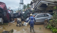 A rescuer walks past piled up cars washed away by floods at the height of Typhoon Kalmaegi in a subdivision of Cebu City in the central Philippines on November 4, 2025. (Photo by Alan Tangcawan / AFP)