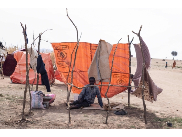 A displaced Sudanese man who fled El-Fasher after the city fell to the Rapid Support Forces (RSF), sits in a makeshift shelter in the Um Yanqur camp, located on the southwestern edge of Tawila, in war-torn Sudan's western Darfur region on November 3, 2025. (Photo by AFP)