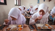 Students eat lunch on the first day of a free-meal program at 11 State Senior High School in East Jakarta on January 6, 2025. Photo by Aditya IRAWAN / AFP

