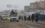 Displaced Palestinian walk past a vehicle carrying others west of Deir al-Balah city in the central Gaza Strip, on November 15, 2025 as a low-pressure system impacts the area. (Photo by Bashar TALEB / AFP)