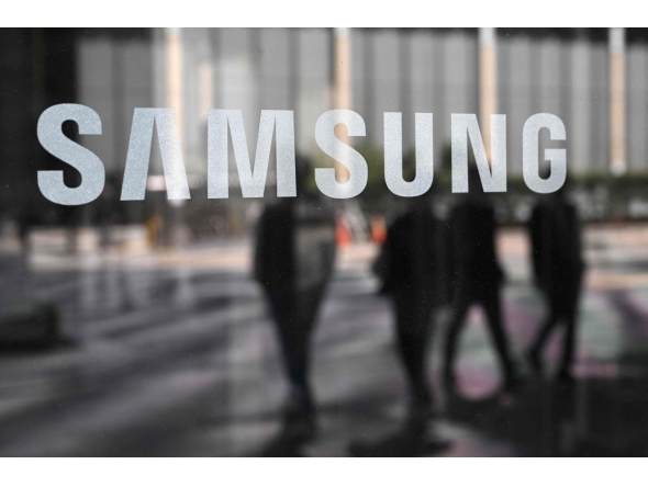 People walk past the Samsung logo displayed on a glass door at the company's Seocho building in Seoul on April 30, 2025. Photo by Jung Yeon-je / AFP