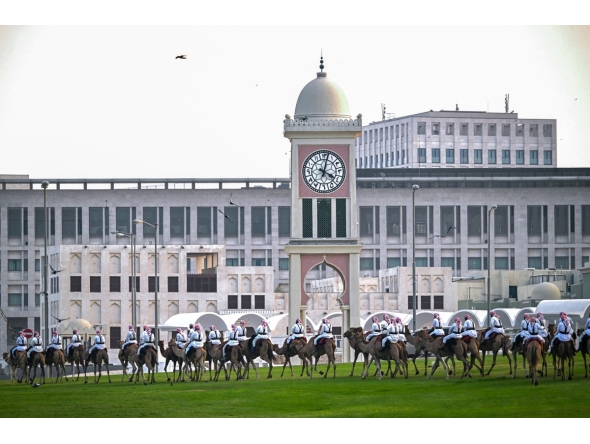Camel-mounted royal guards patrol around the Amiri Diwan in Doha on November 13, 2025. (Photo by MAHMUD HAMS / AFP)