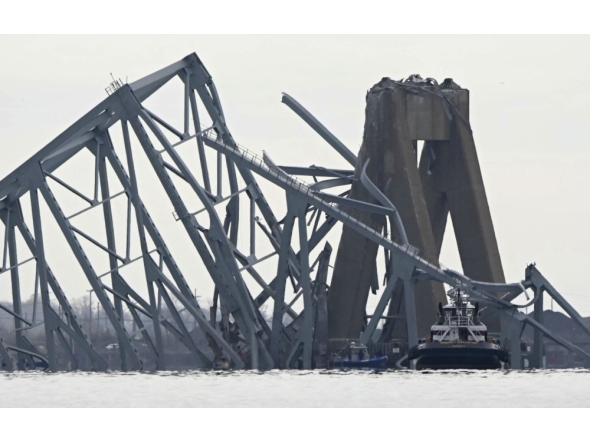 The steel frame of the Francis Scott Key Bridge lies in the water after it collapsed in Baltimore, Maryland, on March 26, 2024. Photo by Mandel NGAN / AFP.

