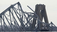 The steel frame of the Francis Scott Key Bridge lies in the water after it collapsed in Baltimore, Maryland, on March 26, 2024. Photo by Mandel NGAN / AFP.

