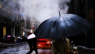 People walk on the street as the rain pours in the Manhattan borough of New York City on November 19, 2025. (Photo by CHARLY TRIBALLEAU / AFP)
