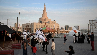 Children and passersby stop to watch men in traditional garb on horseback at the historic Souq Waqif in Qatar on November 26, 2025. (Photo by Mahmud Hams / AFP)