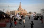 Children and passersby stop to watch men in traditional garb on horseback at the historic Souq Waqif in Qatar on November 26, 2025. (Photo by Mahmud Hams / AFP)