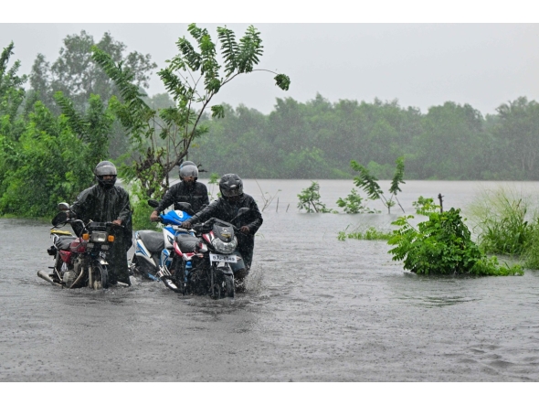 Motorists wade through a flooded street in Biyagama on the outskirts of Colombo on November 28, 2025. (Photo by Ishara S. KODIKARA / AFP)
