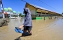 A woman walks past a mosque in a flooded area in Meureudu, Pidie Jaya district in Indonesia's Aceh province on November 30, 2025. (Photo by CHAIDEER MAHYUDDIN / AFP)
