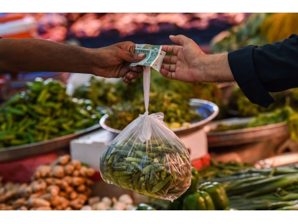 File photo: A customer buys vegetables from a stall at a market in Karachi on July 3, 2023. (Photo by Asif HASSAN / AFP)