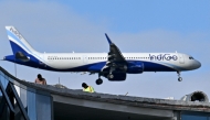 Labourers work atop an under-construction building as an Indigo aircraft prepares to land at Kempegowda International Airport in Bengaluru on December 4, 2025. Photo by Idrees MOHAMMED / AFP