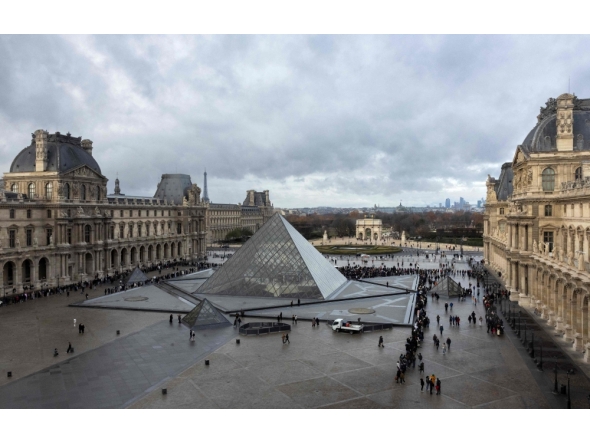 (Files) This photograph shows visitors, seen from the Sully wing, queuing in the Cour Napoleon by the pyramid, to enter the Louvre Museum in Paris on November 19, 2025. (Photo by Sébastien Dupuy / AFP)