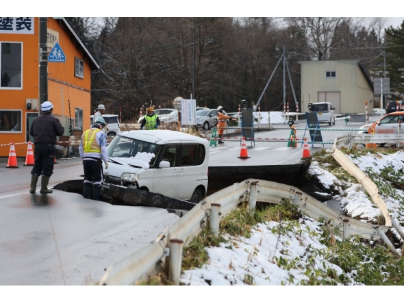 A vehicle is seen on a collapsed road in Tohoku town in Aomori Prefecture on December 9, 2025, following a 7.5 magnitude earthquake off northern Japan. (Photo by JIJI Press / AFP)