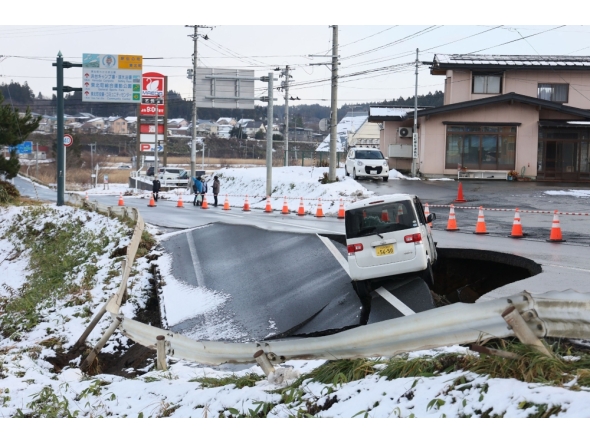 A vehicle rests on the edge of a collapsed road in Tohoku town in Aomori Prefecture on December 9, 2025, following a 7.5 magnitude earthquake off northern Japan. A big quake off northern Japan left at least 30 injured, authorities said on December 9, damaging roads and leaving thousands without power in freezing temperatures. (Photo by JIJI Press / AFP) 