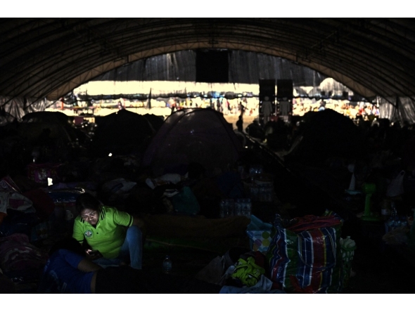 A displaced resident rests at an evacuation center at Chang International Circuit in the Thai border province of Buriram on December 12, 2025. (Photo by Lillian SUWANRUMPHA / AFP)