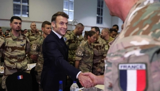 French President Emmanuel Macron shakes hands with a soldier during a Christmas diner with troops of the 5th Cuirassier Regiment's base in Zayed Military City, near Abu Dhabi, on December 21, 2025.(Photo by Ludovic MARIN / AFP)
