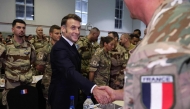 French President Emmanuel Macron shakes hands with a soldier during a Christmas diner with troops of the 5th Cuirassier Regiment's base in Zayed Military City, near Abu Dhabi, on December 21, 2025.(Photo by Ludovic MARIN / AFP)
