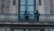 Workers install iron window guards on the window of the Gallerie d'Apollon (Apollo's gallery) of the Louvre Museum, on the Quai Francois Mitterrand side, in Paris on December 23, 2025 a few weeks after thieves used a furniture lift to break into the museum. Photo by Dimitar DILKOFF / AFP