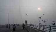 Commuters ride along the Signature Bridge over Yamuna river amid dense smog in NEW DELHI on December 27, 2025. (Photo by Arun SANKAR / AFP)