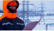 A worker at substation checking documents. Winter conditions highlight complexity and importance of maintaining power supply in cold weather.