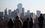 People look out at the view of the skyline of the financial office buildings in the City of London from Primrose Hill in London on January 2, 2026. Photo by HENRY NICHOLLS / AFP