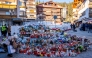 A mourner lays a flower bouquet at a makeshift memorial near the Constellation, on January 4, 2026, in Crans-Montana in honour of the victims of the fire that ripped through the venue in the luxury Alpine ski resort on New Year's Eve. Photo by MAXIME SCHMID / AFP