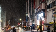 Pedestrians walk with umbrellas as it snows and rains in Tokyo's Akihabara district on January 2, 2026. (Photo by Philip FONG / AFP)
