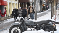 Passers-by walk past a snow-covered motorcycle in the center of Kyiv on January 10, 2026. (Photo by Sergei SUPINSKY / AFP)
