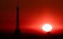 (Files) The sun rises by the Eiffel Tower in Paris on July 1, 2025. (Photo by Thibaud Moritz / AFP)
 