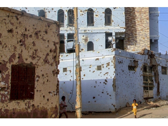 Children photographed near houses damaged with bullets in Omdurman. AFP file photo.