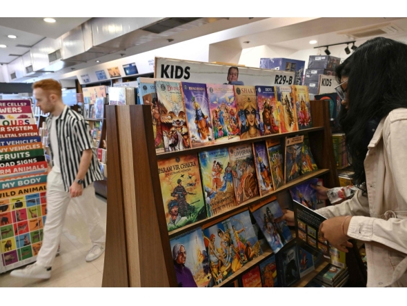 This photograph taken on January 20, 2026 shows a woman checking books by India's oldest and indigenous comic publisher Amar Chitra Katha at a store in Mumbai. (Photo by Indranil Mukherjee / AFP)
