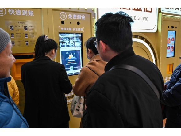 Customers wait to sell their gold jewelry in a Smart Gold Store Machine placed in a shopping mall in Shanghai on January 29, 2026. (Photo by Hector RETAMAL / AFP) 