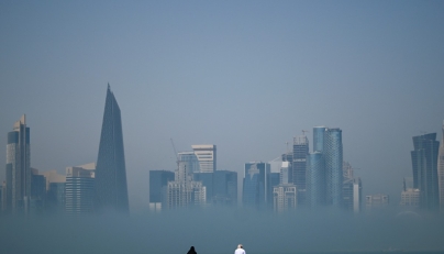 People look at the skyline covered in fog in Doha on February 9, 2026. (Photo by Mahmud HAMS / AFP)
