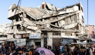 Palestinians shop for food beneath a destroyed building in Gaza City's Zawiya market on February 18, 2026, on the first days of the holy fasting month of Ramadan. (Photo by Omar AL-QATTAA / AFP)