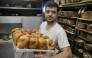 French volunteer baker Loic Nervi holds a basket of freshly baked bread in his mobile bakery in Borodyanka, Kyiv region on February 19, 2026. (Photo by Genya Savilov / AFP)